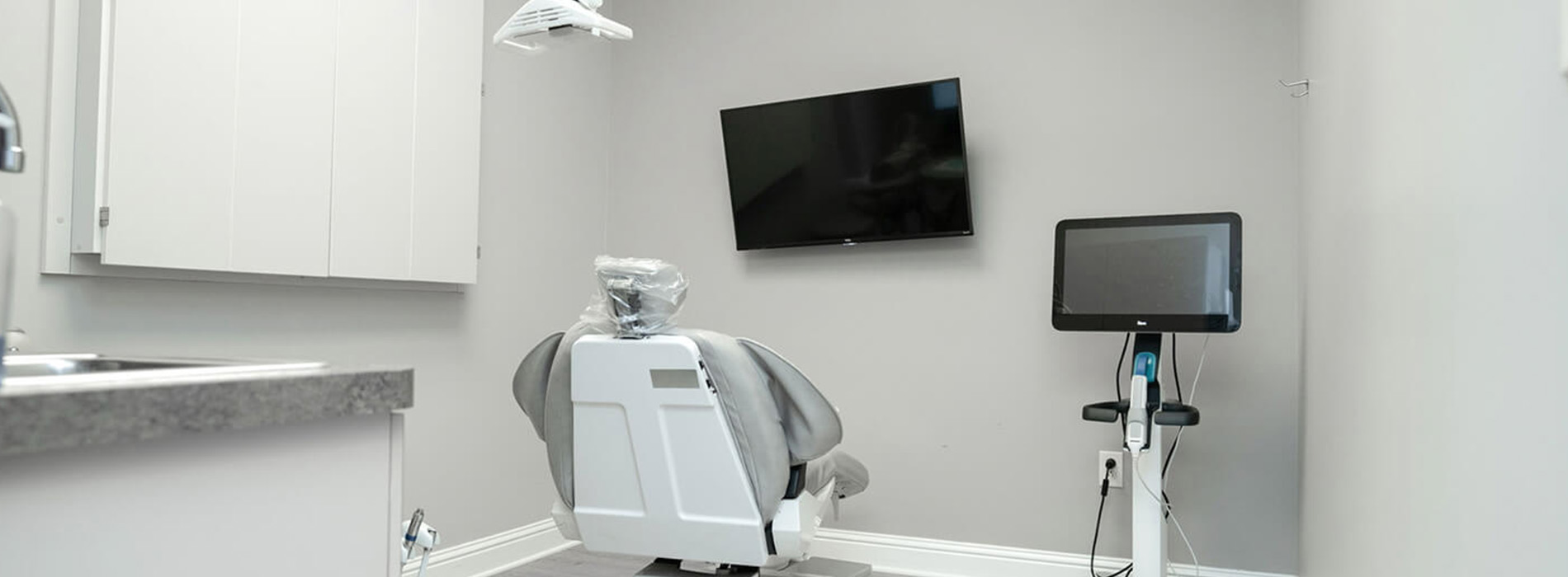 The image shows a modern dental clinic interior with various pieces of equipment, including a dental chair and an X-ray machine.