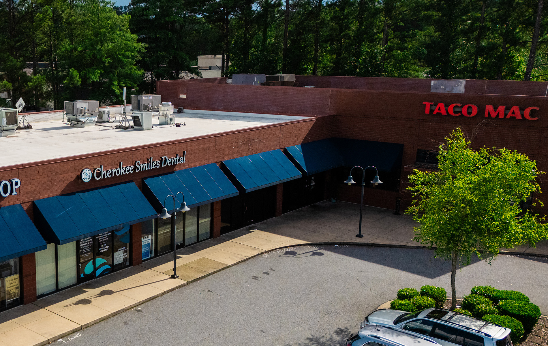 The image shows a commercial building with a sign that reads  Taco Mac  on its facade, located at an intersection with other businesses.