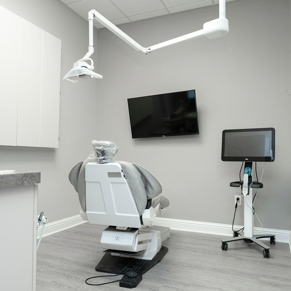 The image shows a dental office interior with a dental chair, a dental light, and various dental equipment.