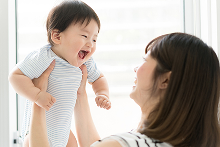 A woman holding a baby with an open mouth, likely expressing surprise or joy.