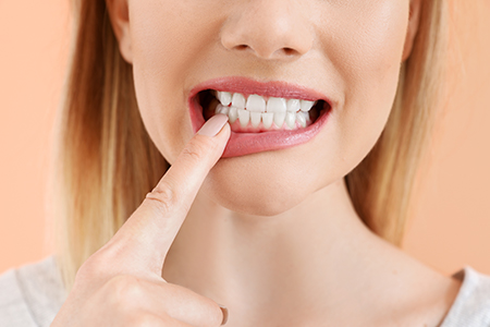A woman with her finger on her teeth, possibly indicating dental care or oral hygiene.